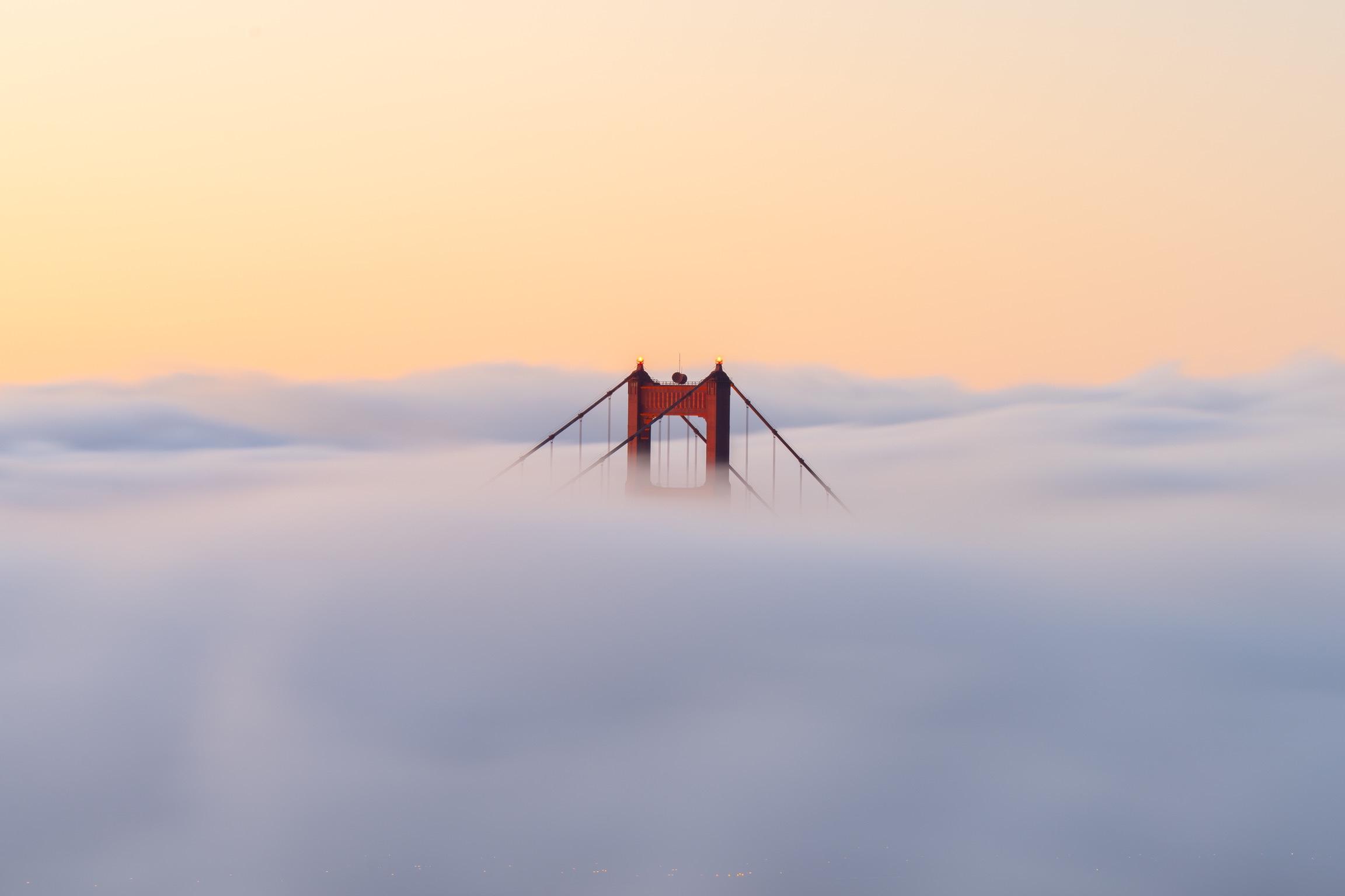The Golden Gate Bridge’s north tower rising above the fog at sunrise